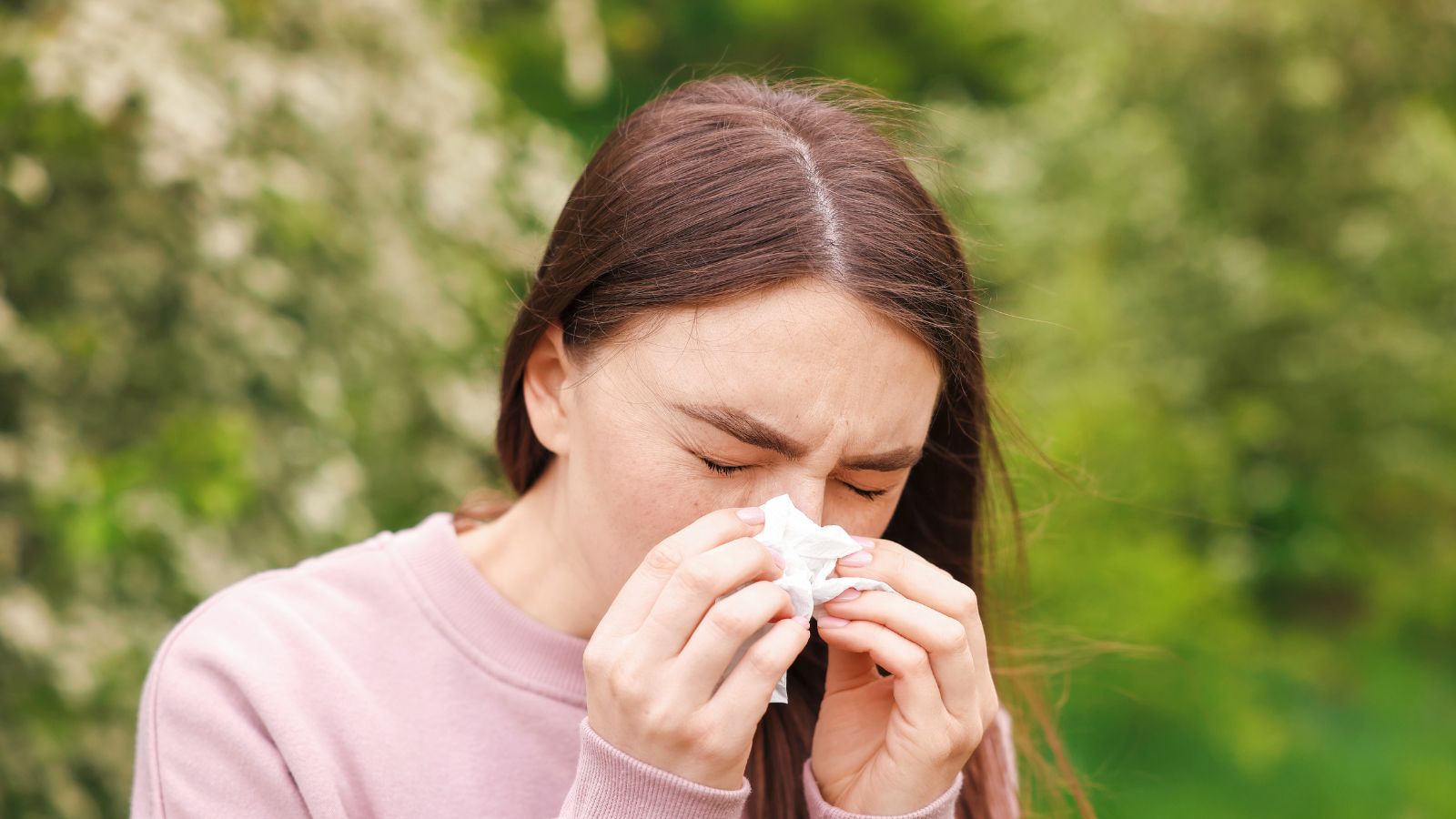 Donna che starnutisce a causa delle allergie primaverili ai pollini, test allergologici disponibili presso il Poliambulatorio Exacta a Modena.